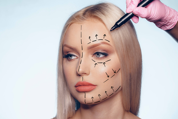 Beautiful blonde woman, being prepared for a cosmetic procedure. Doctor drawing operation lines on her.